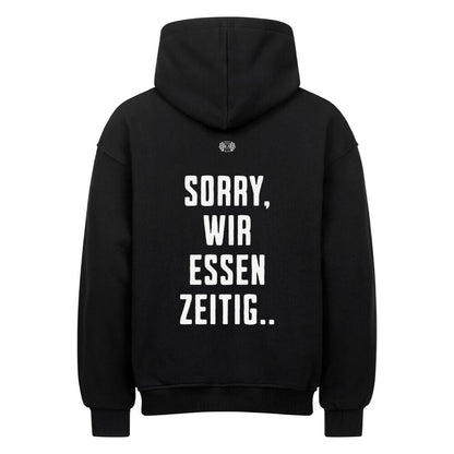 Schwarzer Oversized Hoodie mit großem Rückenprint „Sorry, wir essen zeitig“ im kontrastreichen Mazares Racing Design.